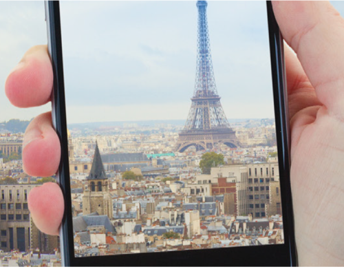 Cybersecurity while traveling image - person holding phone taking picture of eiffel tower