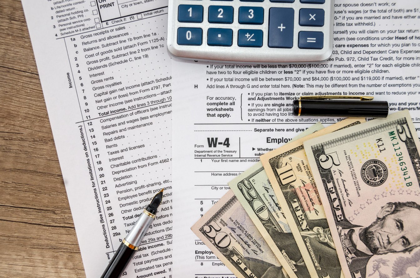 tax form W-4 with dollar, pen and calculator